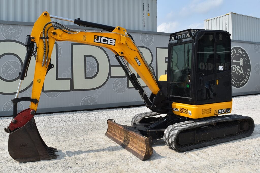 Yellow JCB mini excavator with black cab at auction site.