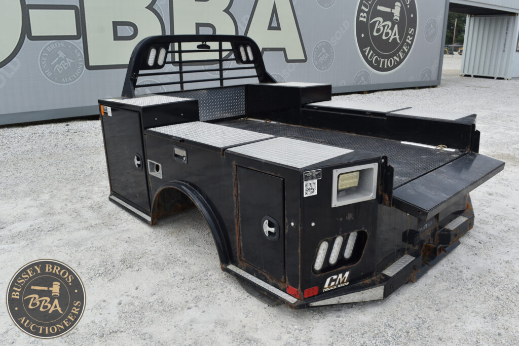 Black flatbed truck for heavy equipment at auction site.