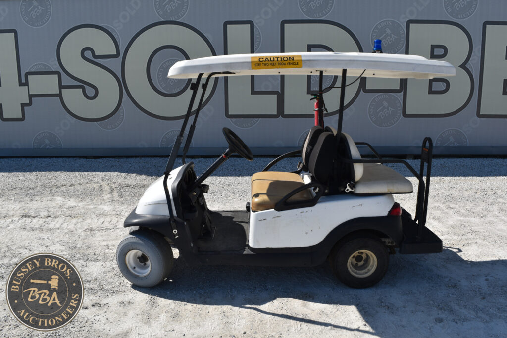 White golf cart with beige seats and a caution sign on the roof.