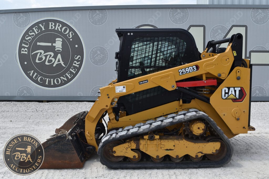 Yellow CAT compact track loader at Bussey Bros Auction with logo in background.