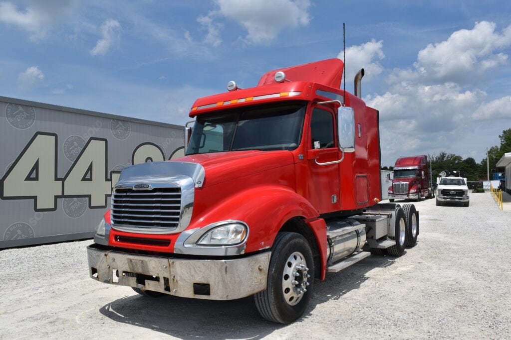 Red semi-truck at heavy equipment auction event.