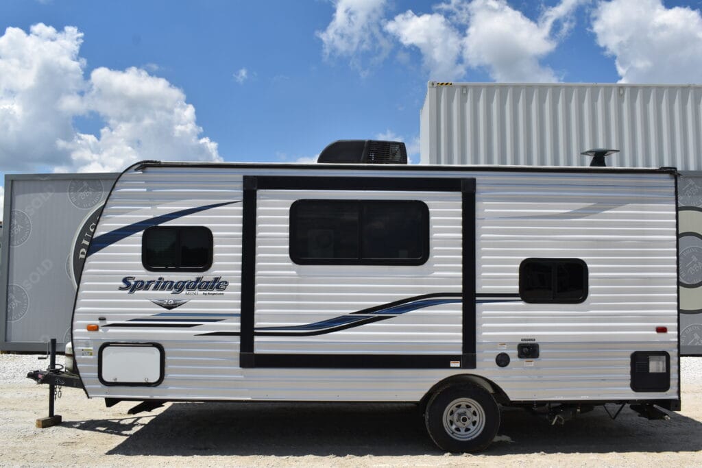 White Springdale travel trailer with black and blue accents at auction.