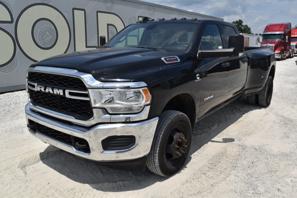 Black RAM pickup truck at Bussey Bros Auction with heavy equipment in background.