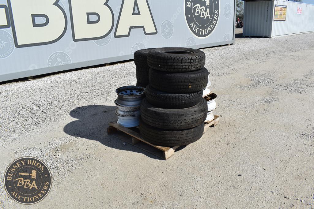 Stack of used tires on wooden pallet outside auction yard.