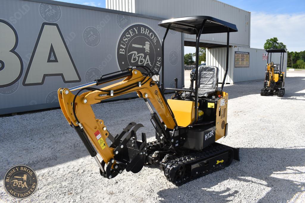 Mini excavator with tracked undercarriage, yellow and black, outdoor auction lot.