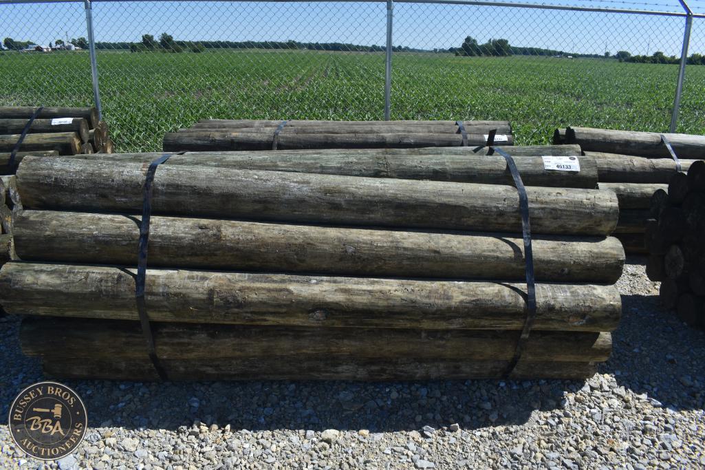 Wooden logs stacked outdoors for sale at Bussey Bros Auctioneers.