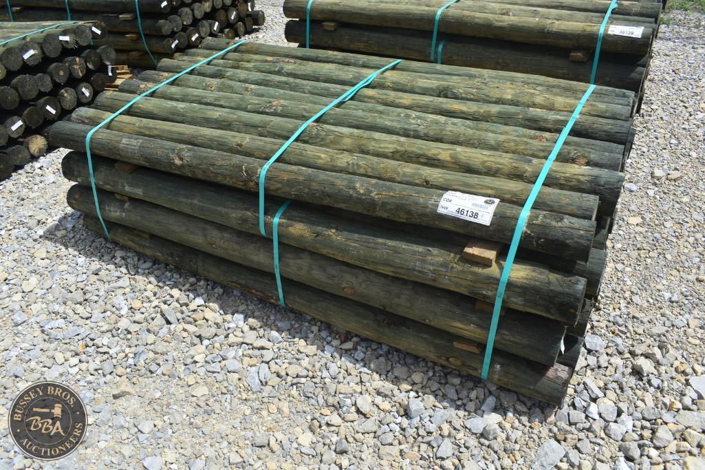 Wooden fence posts stacked and secured with blue straps at auction yard.