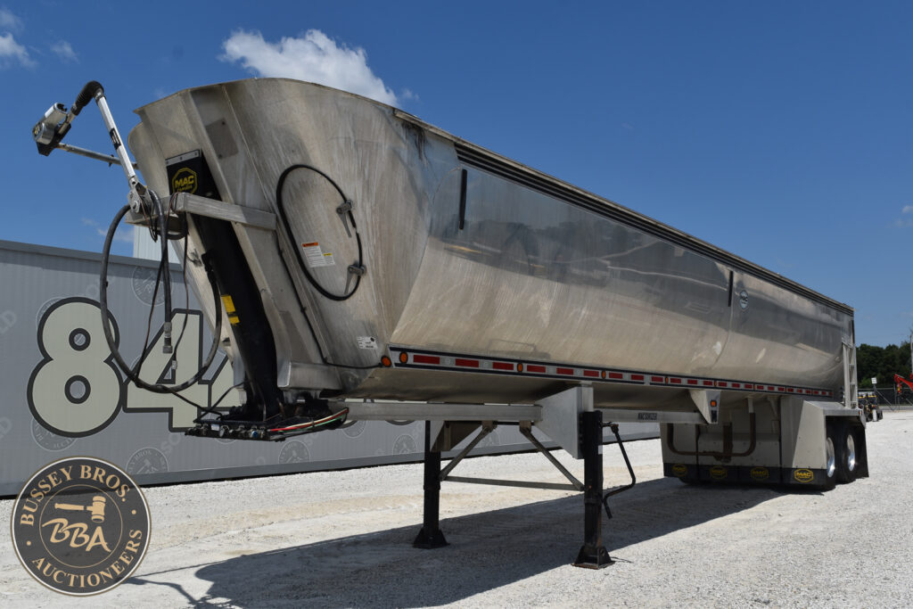 Large semi-trailer for heavy equipment at auction site under blue sky.