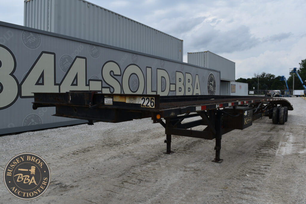 Flatbed trailer with large signage for Bussey Bros Auctioneers at heavy equipment sale.