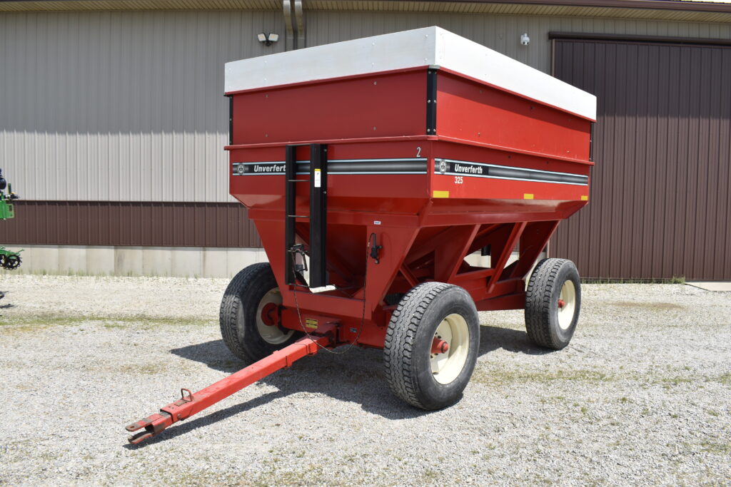 Red farm fertilizer spreader with wheels at auction site.