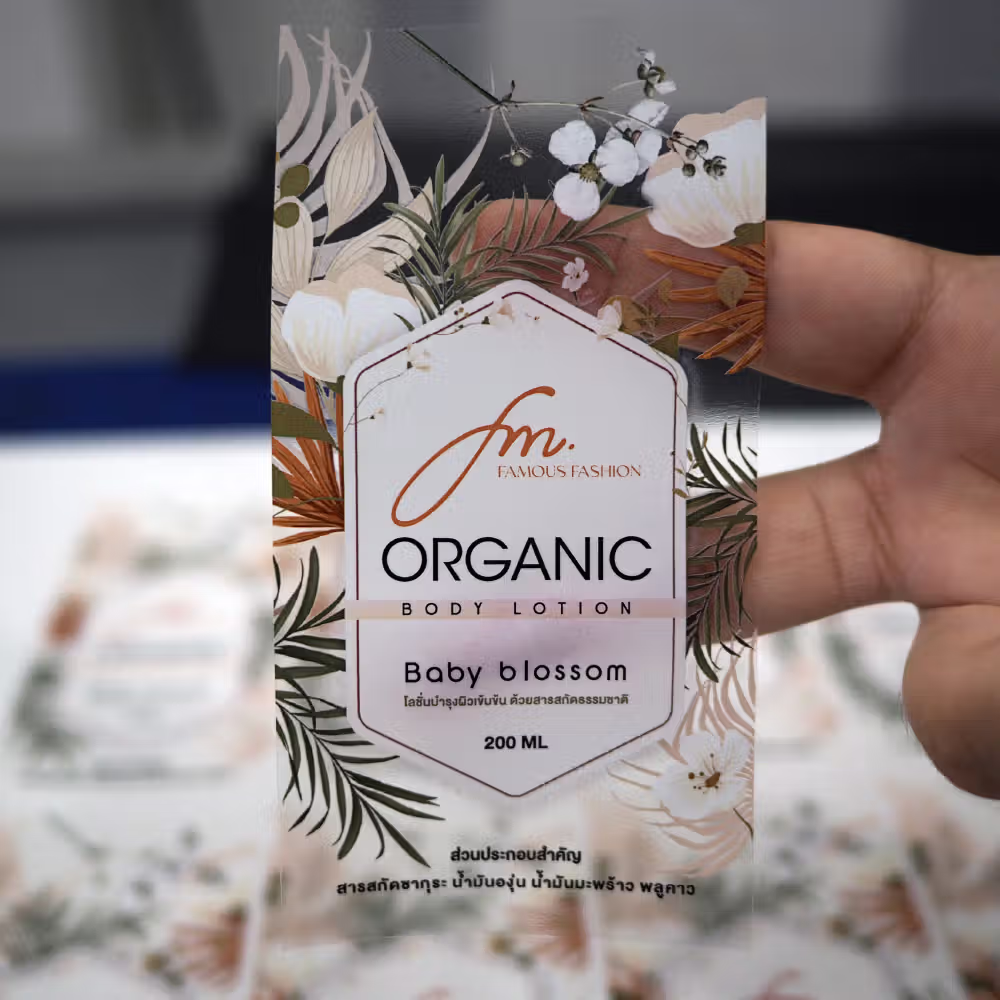 ฉลากสติกเกอร์บอดี้โลชั่น เนื้อ PP ใสพิมพ์ 5 สีพร้อมหมึกขาวรองพื้น (White Ink) ช่วยให้โลโก้และตัวหนังสือขนาดเล็กคมชัดอ่านง่าย กันน้ำและน้ำมันจากเนื้อครีมได้ดีเยี่ยม ติดแน่นไม่หลุดลอกสำหรับบรรจุภัณฑ์เครื่องสำอาง