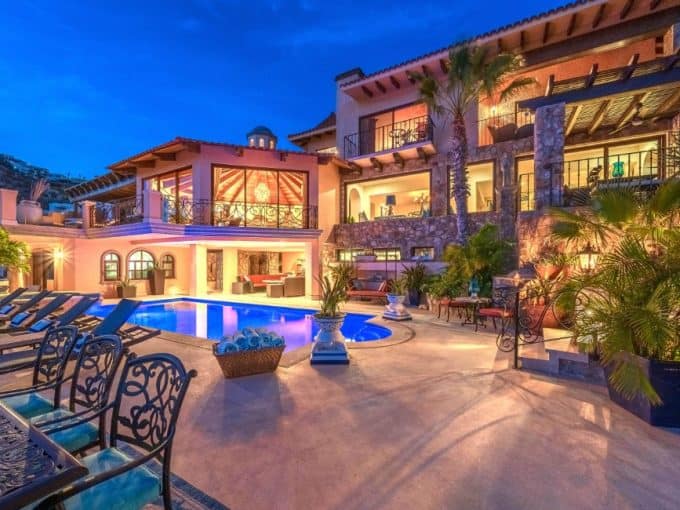 Cabo Del Sol Luxury Home For Sale With Illuminated Pool, Stone Architecture, And Mountain Views At Dusk