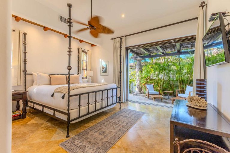 Elegant master suite at 1 La Riviera in Cabo del Sol featuring a four-poster bed, marble floors, and private terrace with garden views.