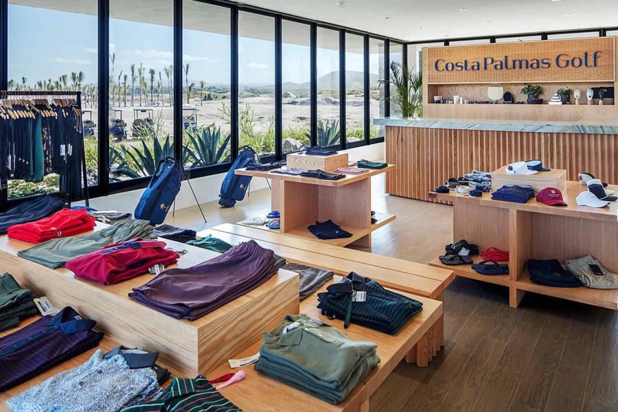 Luxurious Golf Resort Boutique Shop At Cabo Del Sol With Upscale Apparel And Accessories, Showcasing Elegant Interior Design And Scenic Desert Views Outside.