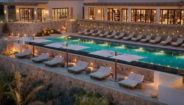 Cabodelsol-Spa Luxurious Outdoor Infinity Pool With Lounge Chairs, Umbrellas, And Ambient Lighting At Cabo Del Sol Luxury Real Estate Property.