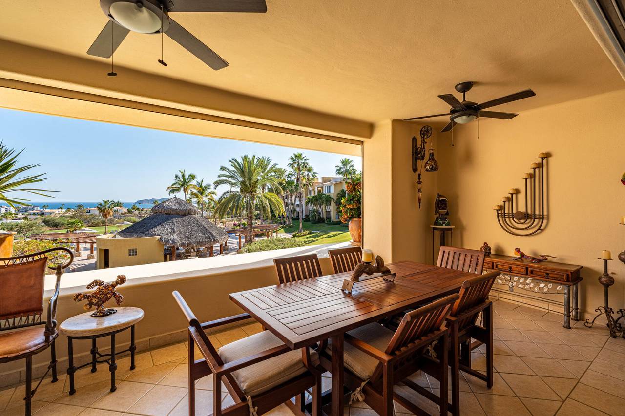 Spacious Indoor Dining Area At Cabo Real With A View Of Lush Palm Trees And The Ocean In The Background, Perfect For Enjoying Meals In A Tropical Setting.