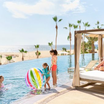 Family Enjoying The Beachfront Infinity Pool At Hilton Los Cabos In Cabo Real