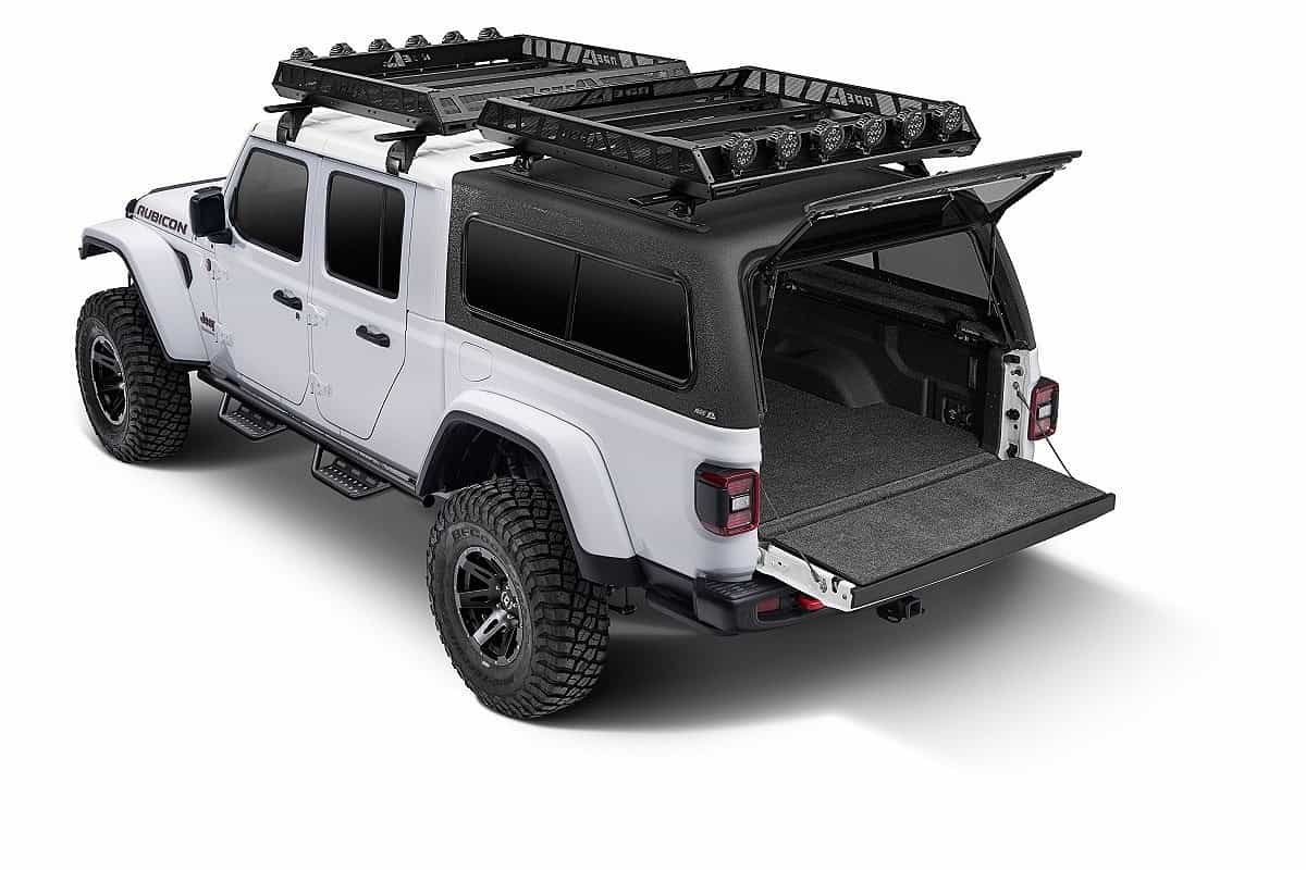 Detailed image of a rugged white Jeep Gladiator with off-road tires, roof racks, and open cargo bed, perfect for outdoor adventures.