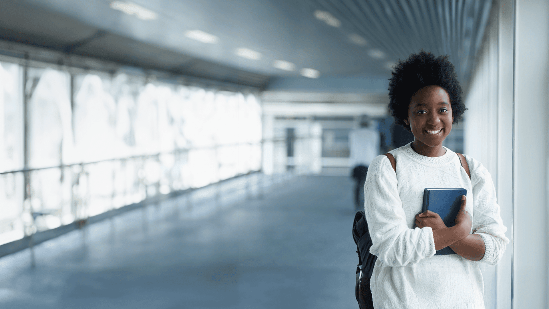 Junge Frau mit Buch und Rucksack – persönliche Weiterbildung für die berufliche Zukunft
