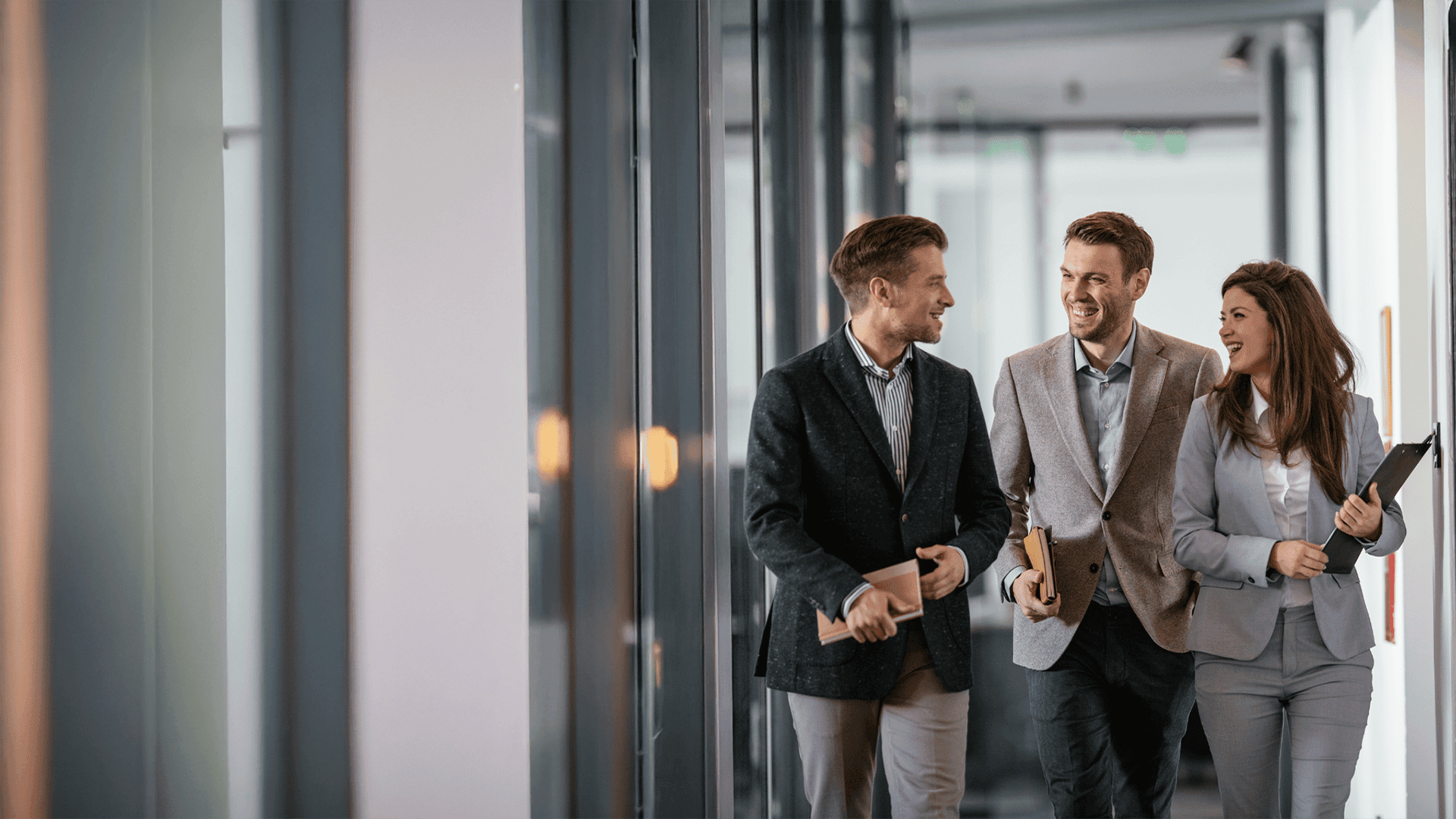 Drei Geschäftsleute im Gespräch auf dem Flur – partnerschaftliche Zusammenarbeit und Weiterbildungslösungen für Unternehmen