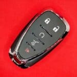 Remote car key with lock and unlock buttons on a red background.