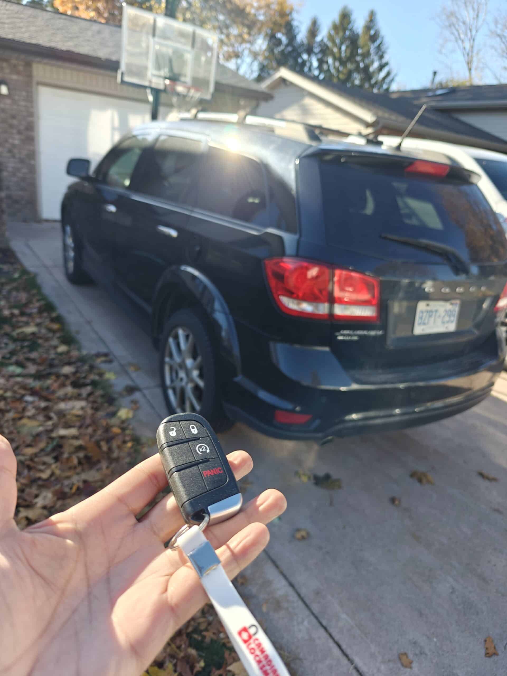 Key fob and car in driveway during daytime, showcasing emergency locksmith services in Lasalle.