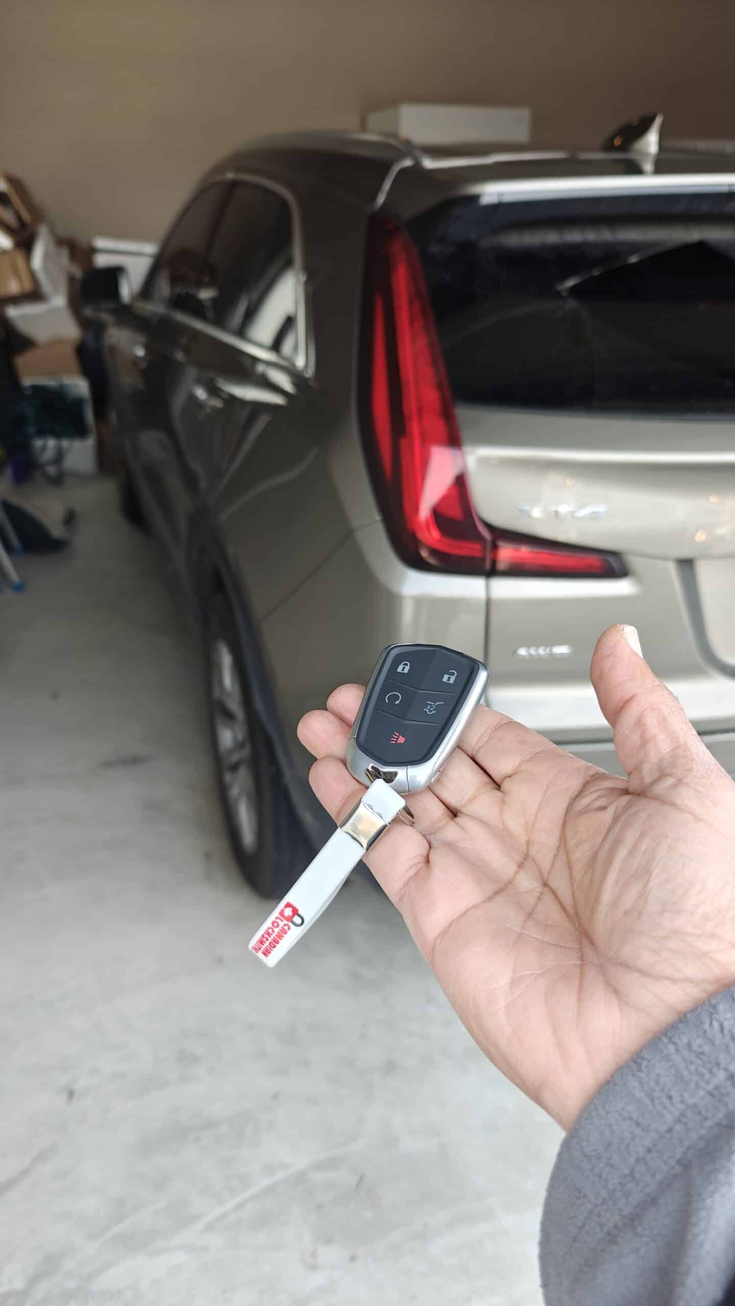 Key fob with emergency lock-unlock buttons held in front of a car in Tecumseh