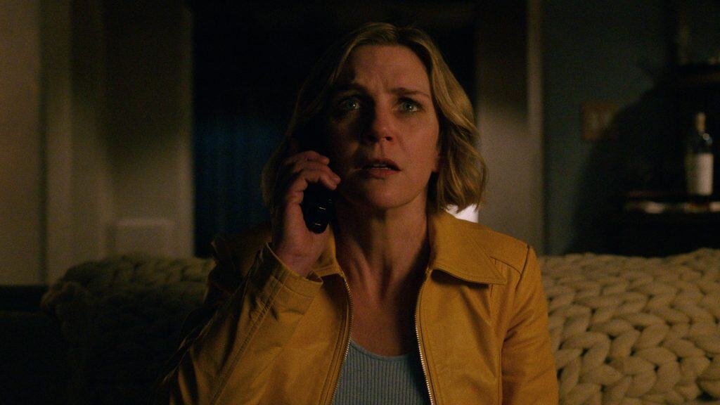 Woman on the phone with a concerned expression, indoors at night.