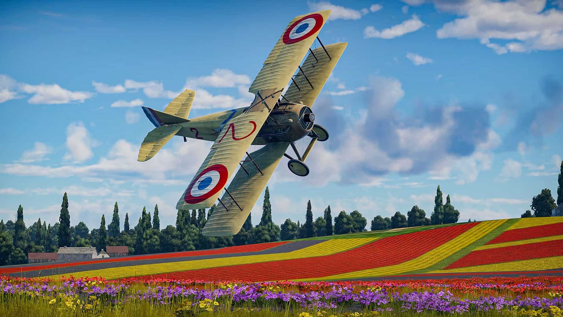 Vintage biplane flying over colorful tulip fields in a rural landscape.