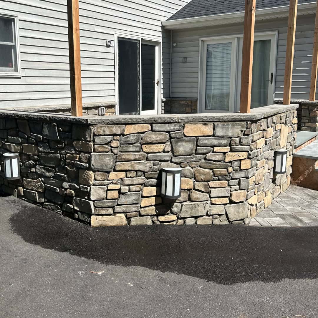 Custom stone retaining wall with outdoor lighting for landscaping.