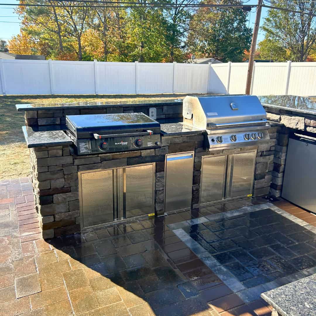 Grill station with two gas grills and outdoor kitchen setup in backyard.