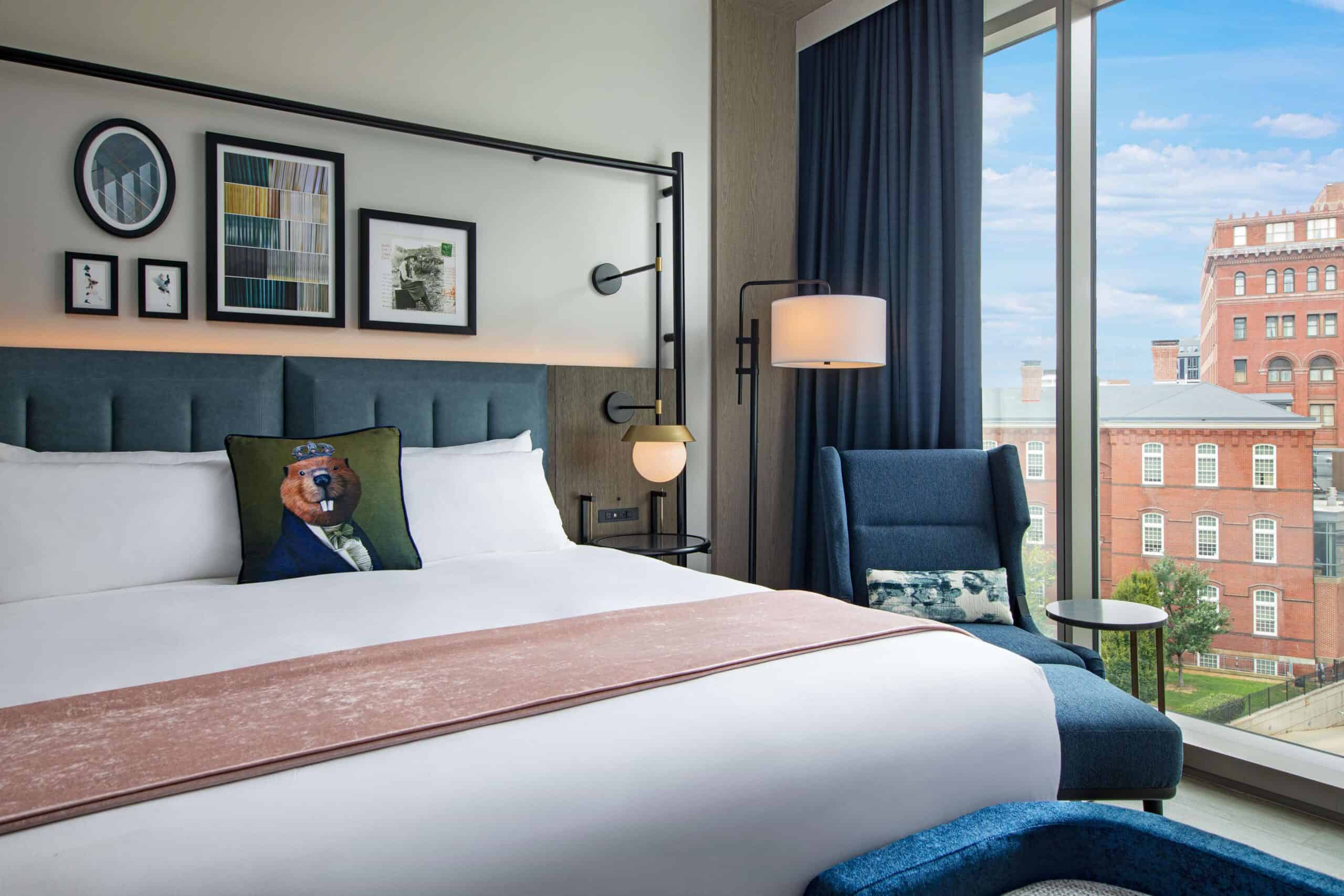 A room at The Royal Sonesta Capitol Hill featuring a pillow with a mascot design, large windows, and a view of the city outside.