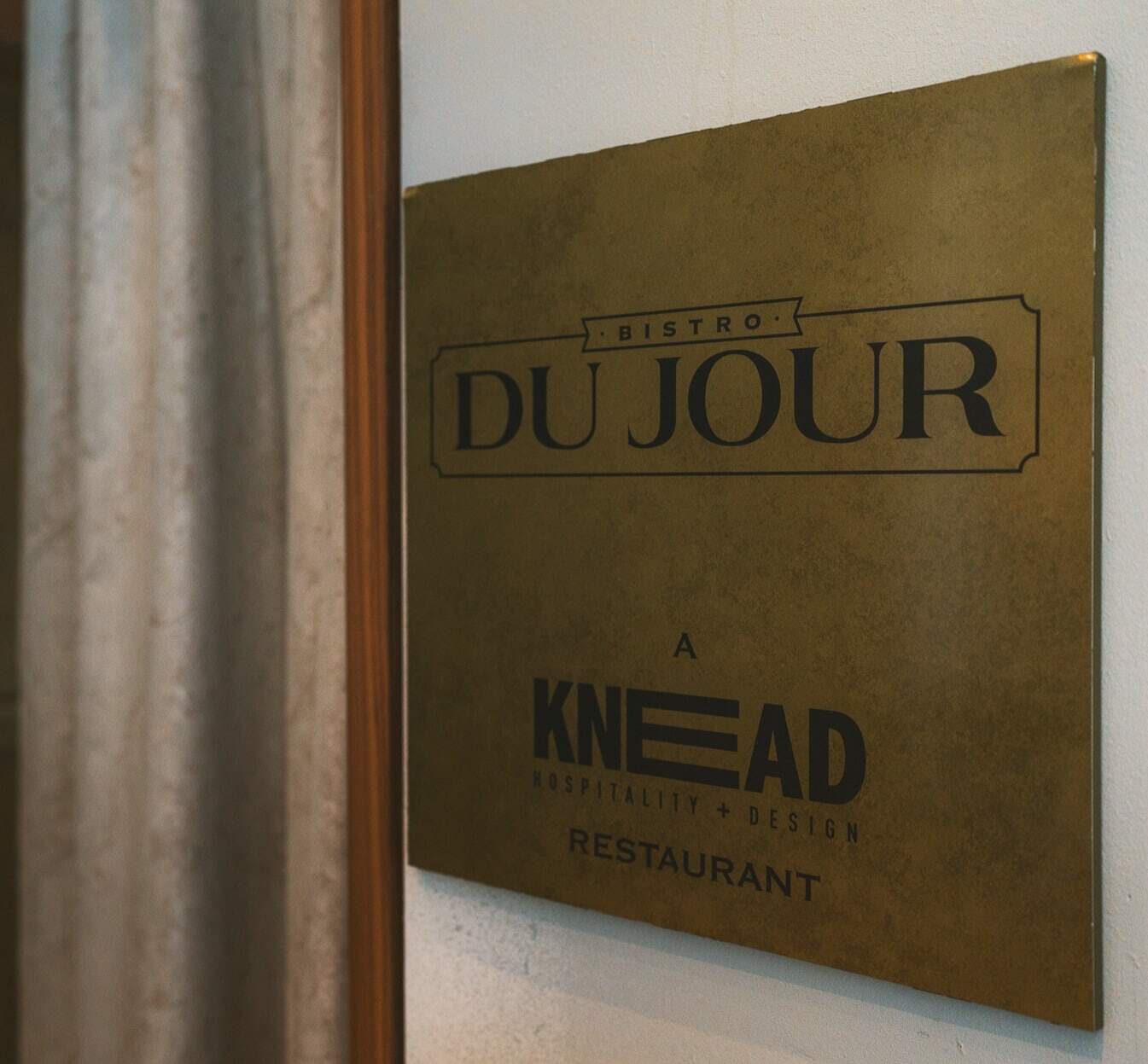 A golden nameplate with the Bistro Du Jour restaurant's name at the entrance.