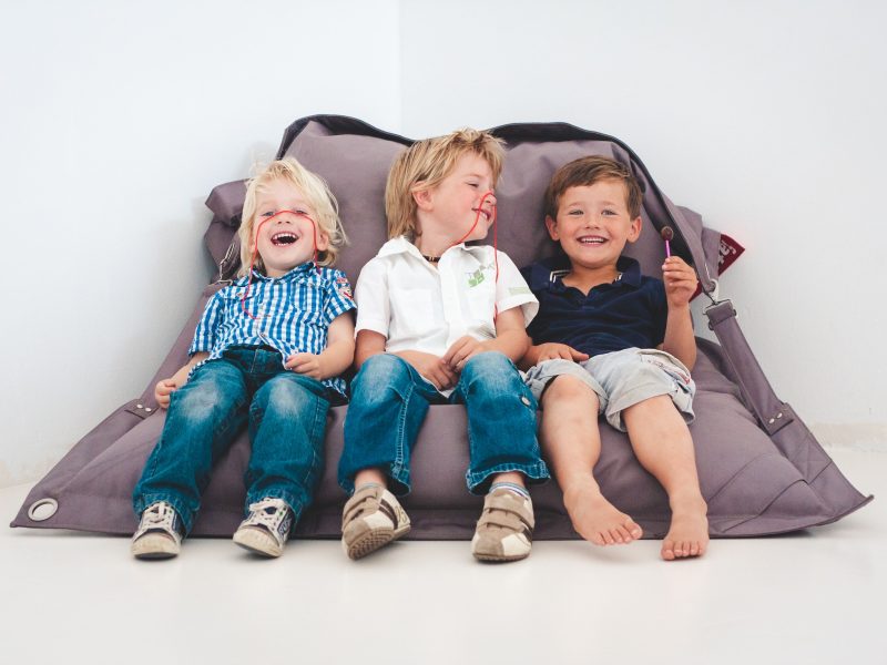 Ongedwongen familiefotografie - drie jongetjes zitten grijnzend op een zitzak snoep te eten