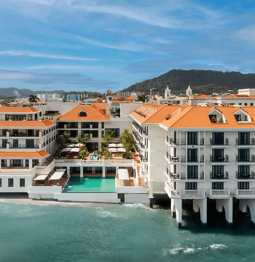 Aerial view of Sofitel Legend Casco Viejo with oceanfront pool, coral-tiled rooftops, and colonial architecture.