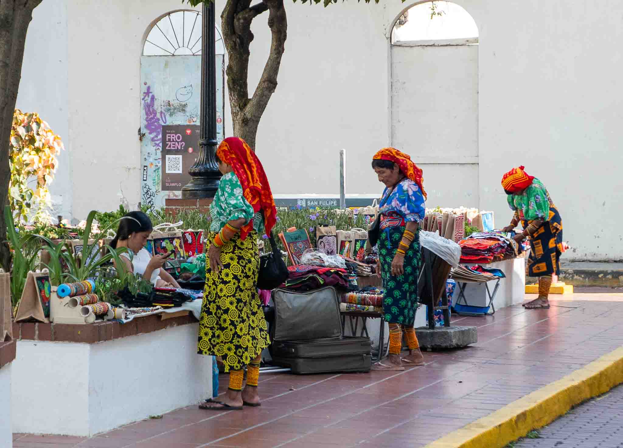 Guna women in traditional dress preparing artisan stalls with handmade crafts on Avenida A in Casco Viejo, Panama