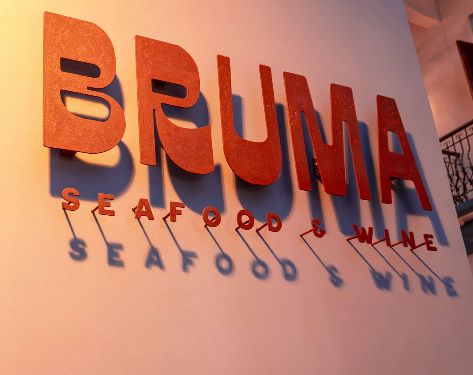 BRUMA Seafood & Wine restaurant sign illuminated against a golden wall in Casco Viejo