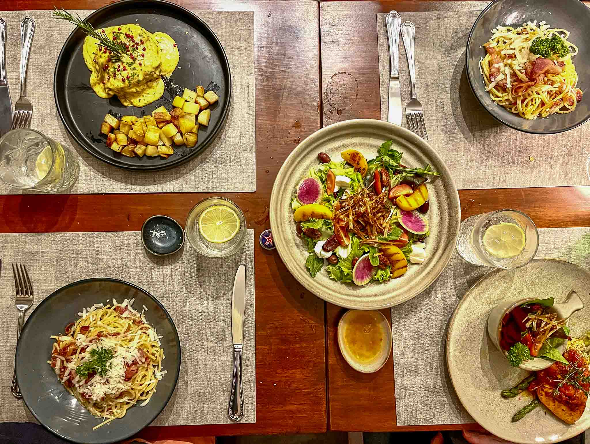 Overhead view of assorted dinner plates at Rosas in Casco Viejo, including pasta, salad, seafood, and potatoes