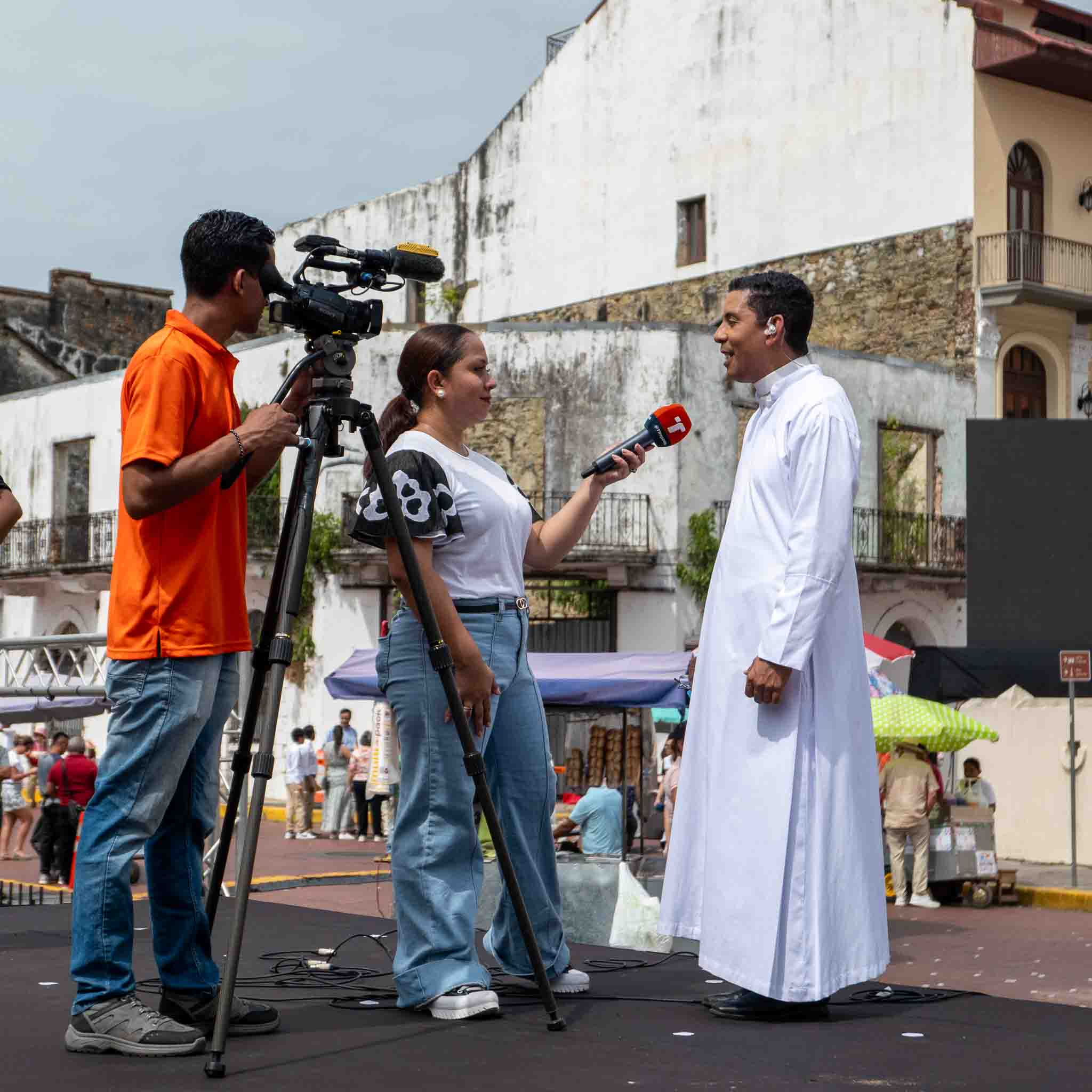 TV reporter interviewing a priest on a street stage in Casco Viejo during a public event or cultural festival