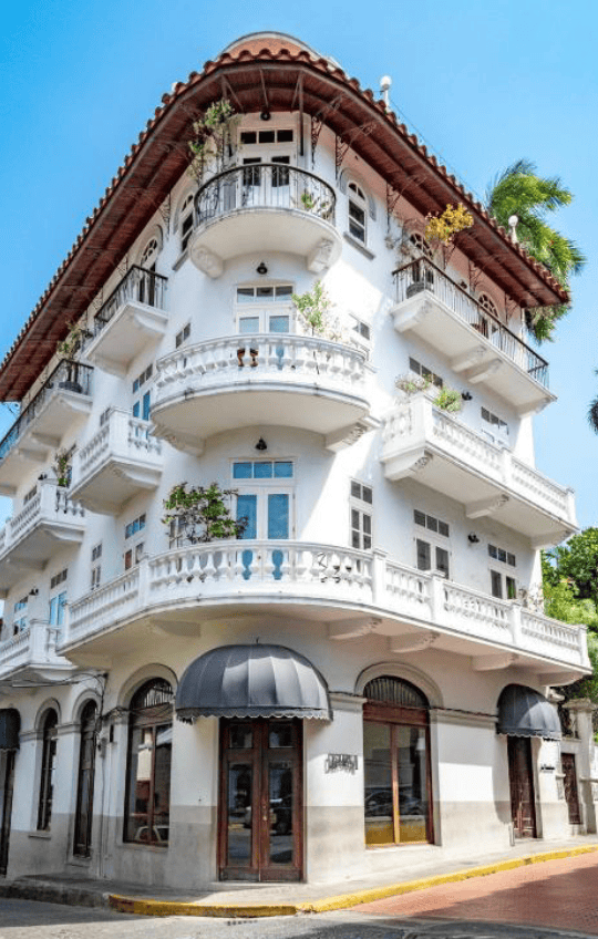 White colonial-style corner building in Casco Viejo with wrought-iron balconies, terracotta roof, and French architectural detailing.