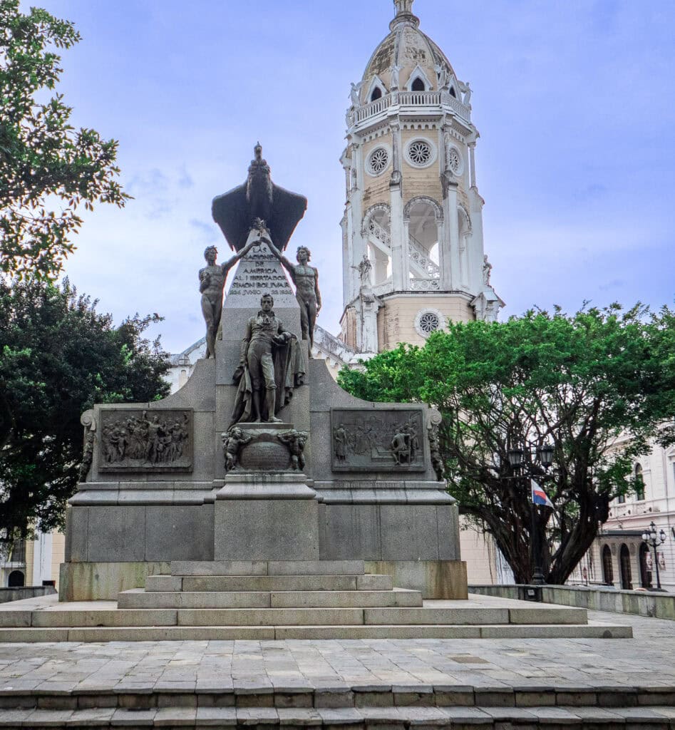 Statue of Justo Arosemena in Plaza Catedral, Casco Viejo, with the bell tower of the Metropolitan Cathedral rising in the background beneath a clear sky.