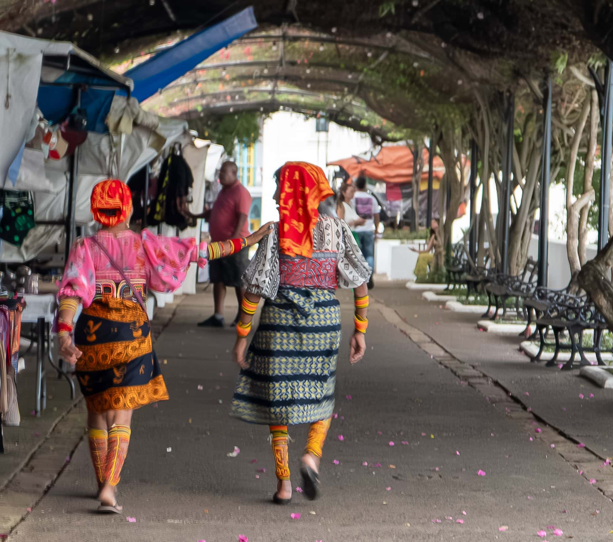 Two Guna women in traditional dress walking along the waterfront promenade in Casco Viejo, Panama