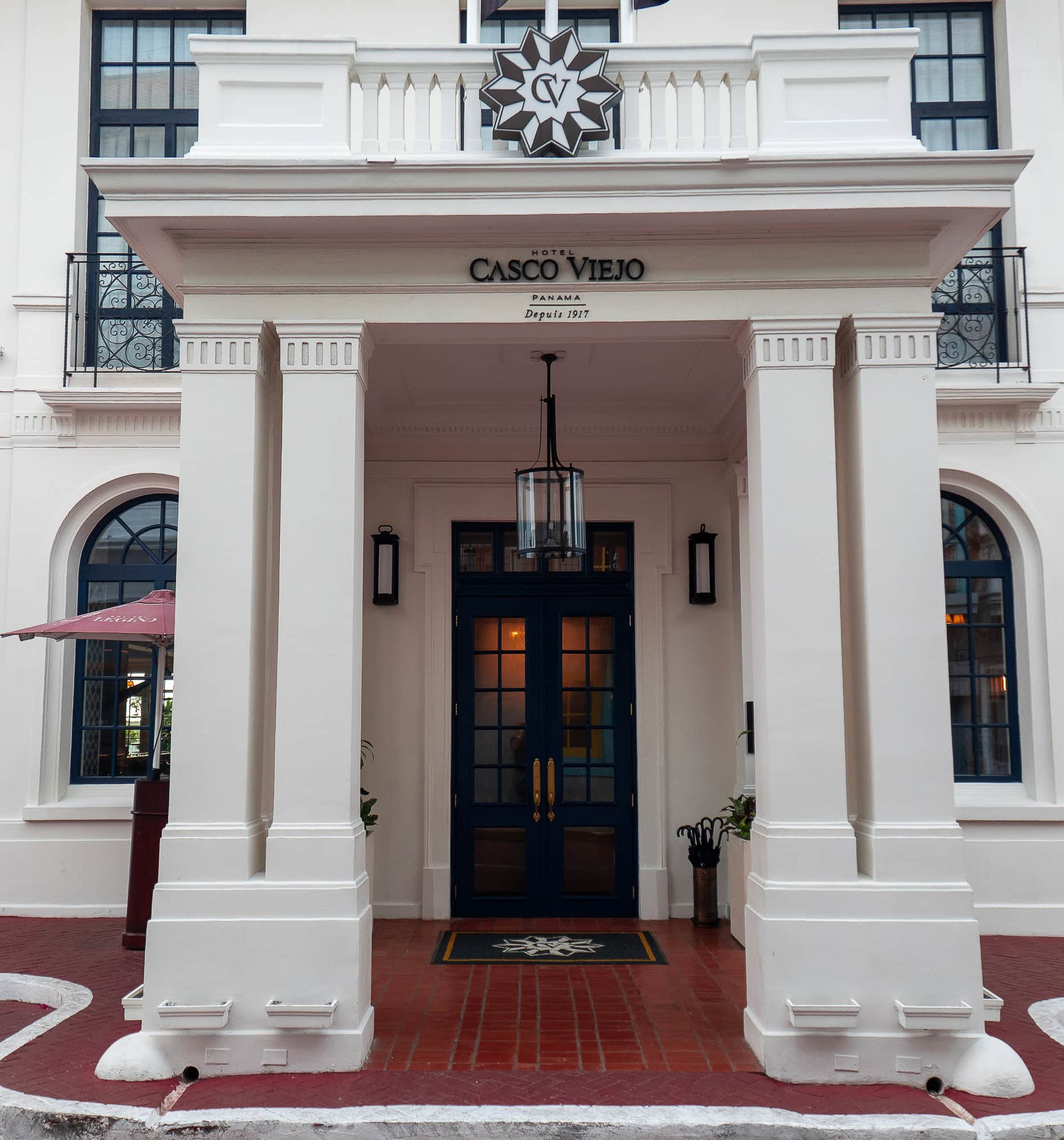 Entrance of Hotel Casco Viejo in Casco Viejo Panama, with white columns and navy double doors.