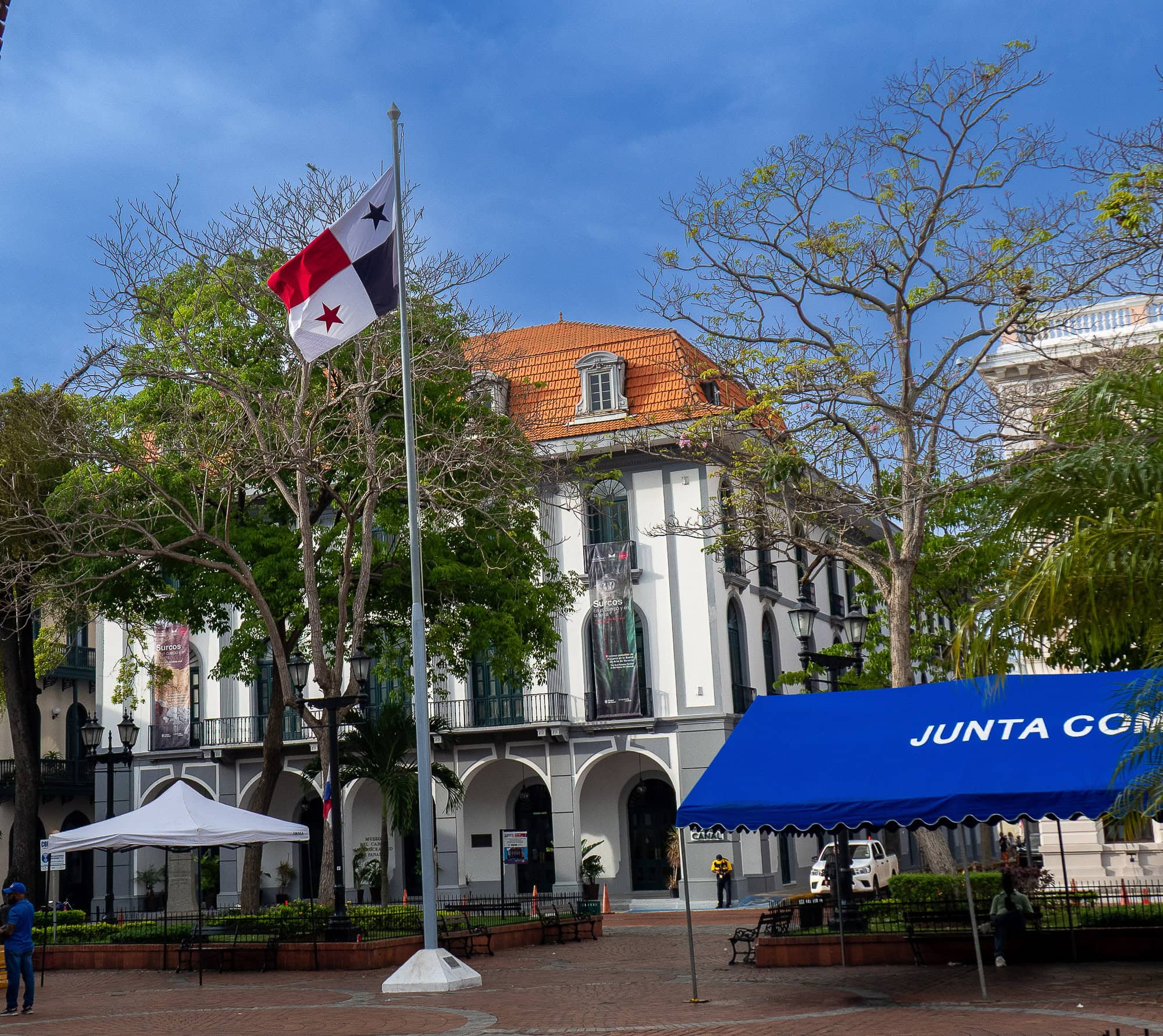 Panama flag waving over Plaza Catedral with Museo del Canal and protest tents in Casco Viejo, Panama.