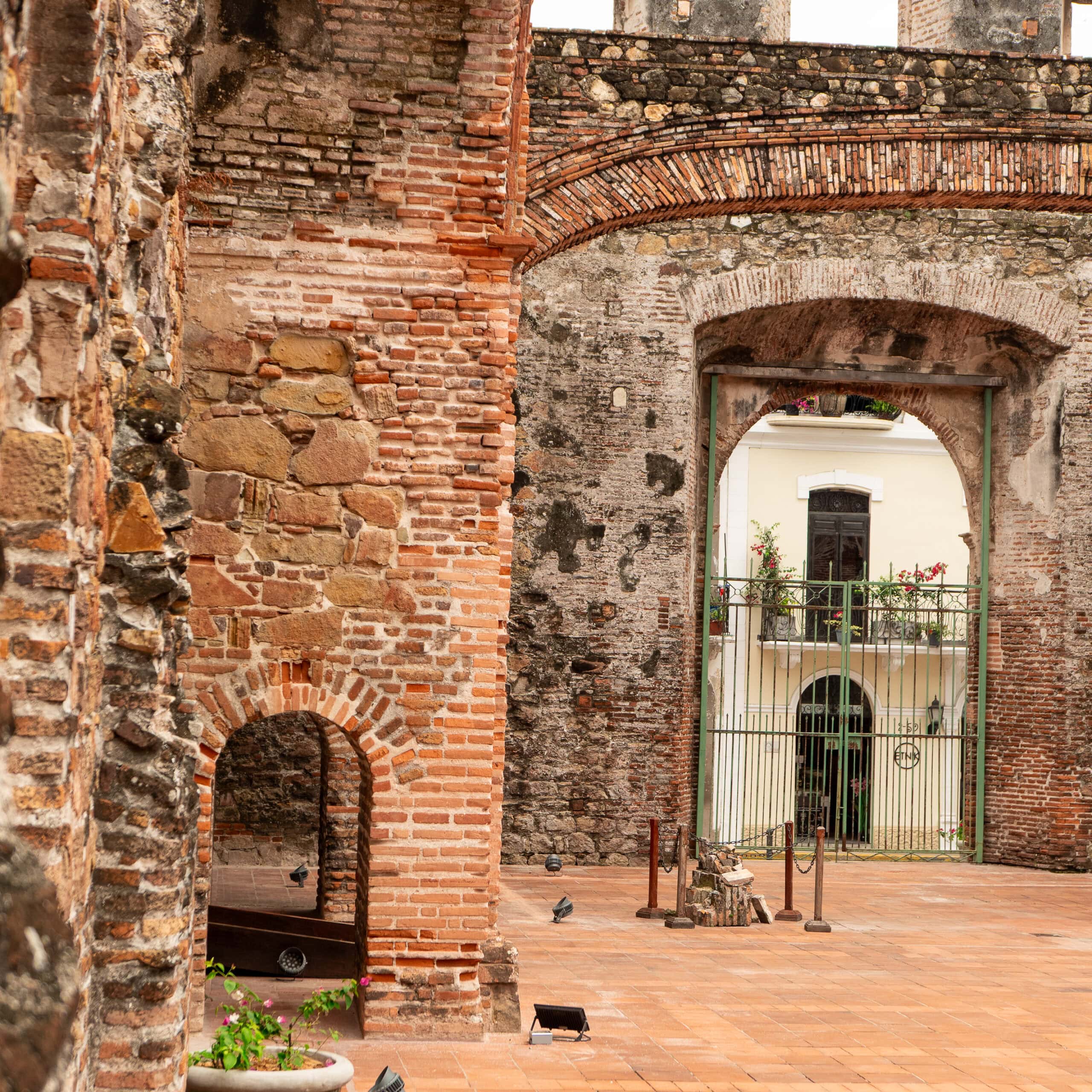 View from inside the Flat Arch ruins in Casco Viejo, showing arched stone walls and a gated entrance framing a colonial building across the street.