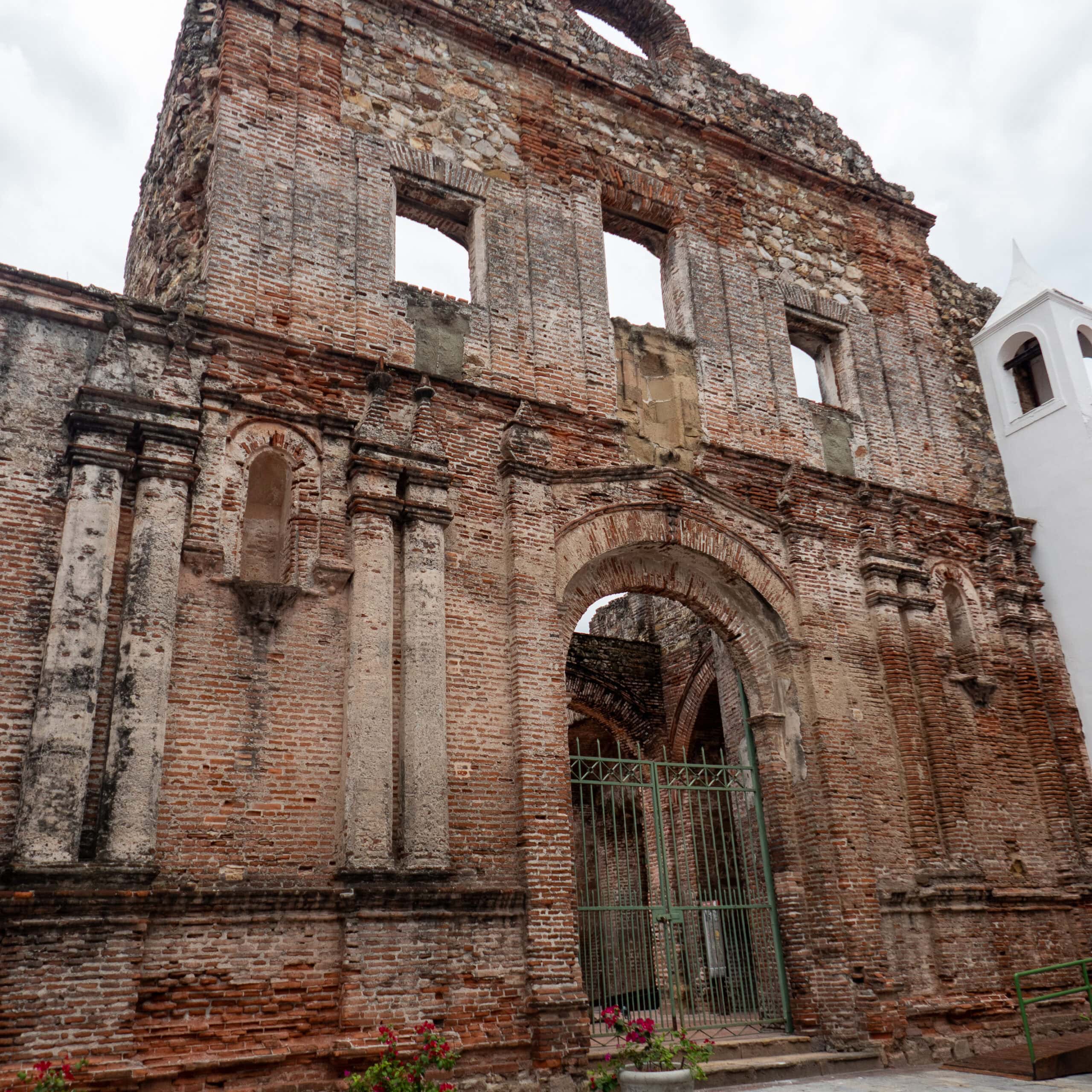 Flat Arch ruins in Casco Viejo, with preserved stone façade and adjacent white colonial bell tower.