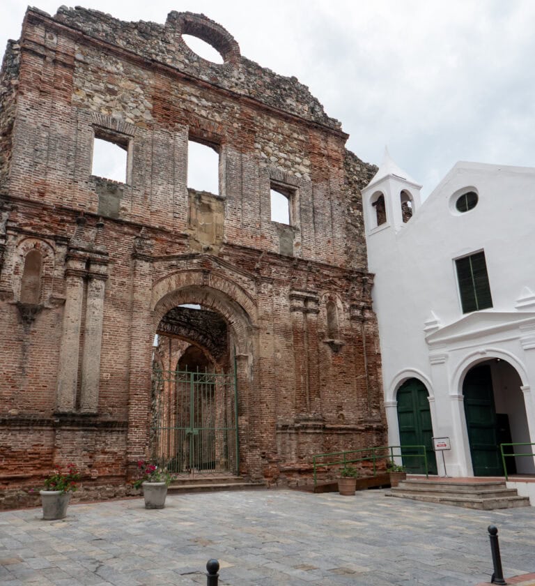 Flat Arch ruins in Casco Viejo, with preserved stone façade and adjacent white colonial bell tower.