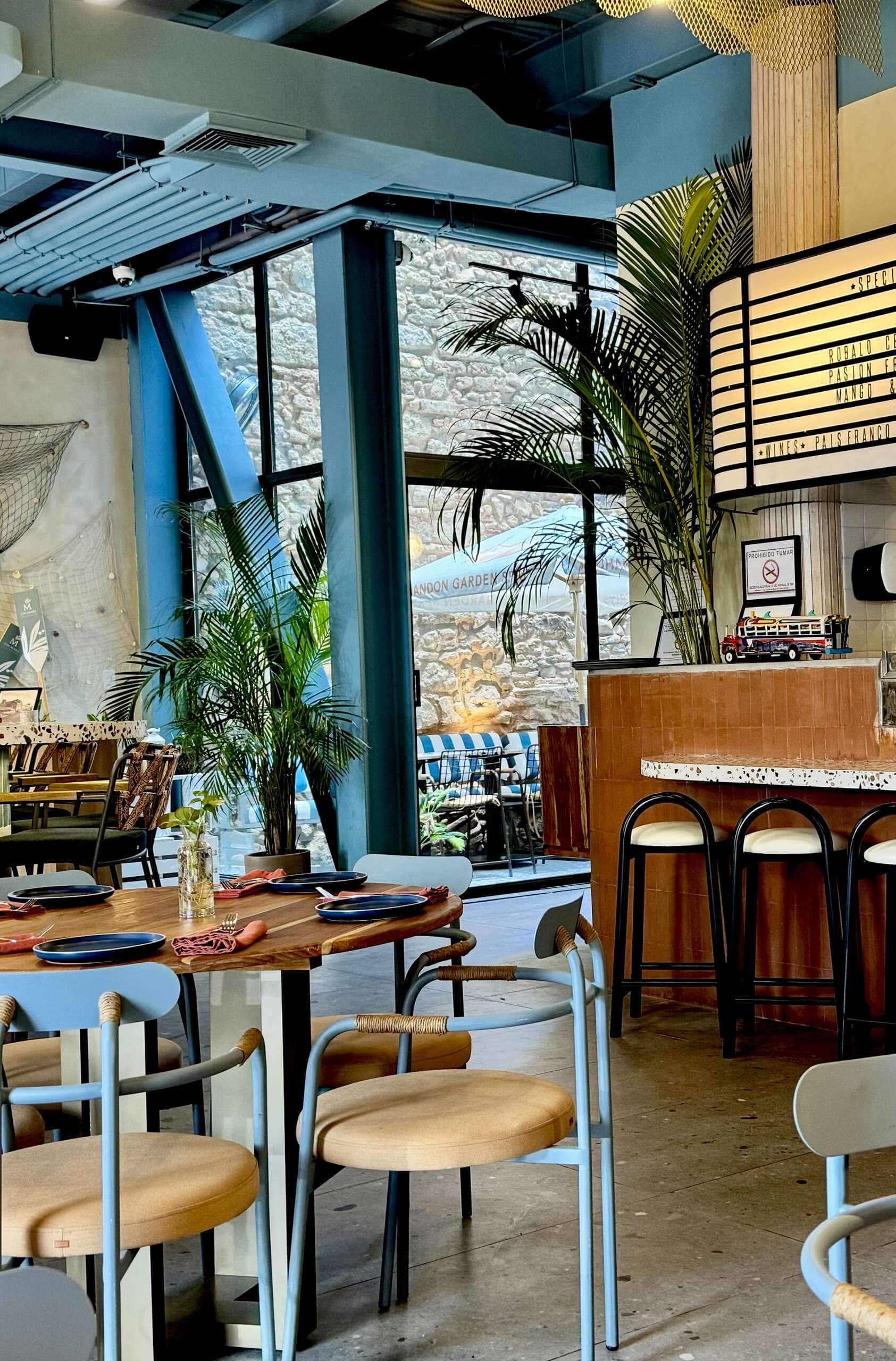 Stylish modern café in Casco Viejo with indoor plants, terrazzo bar, and soft pastel chairs.