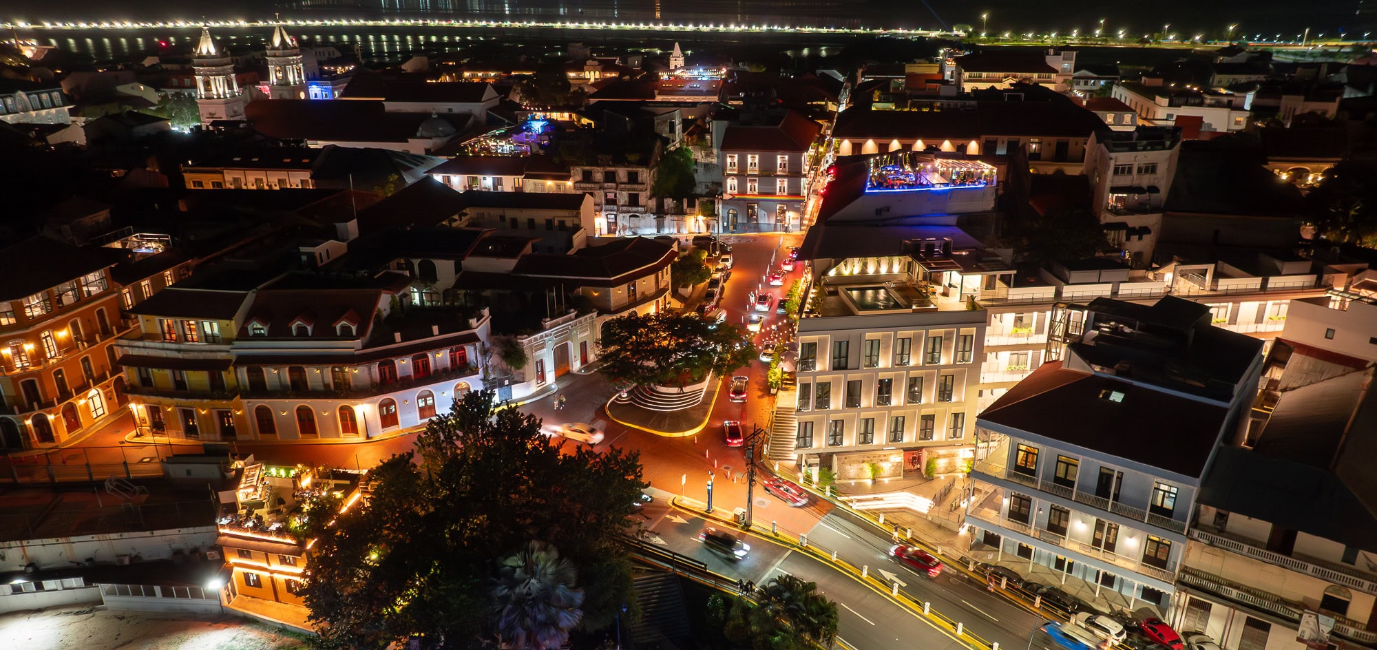 Nighttime view of Casco Viejo, Panama, highlighting rooftop bars, colonial architecture, and illuminated streets against the bay backdrop.