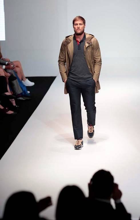 Male model walking the runway at Panama Fashion Week in a stylish, layered outfit